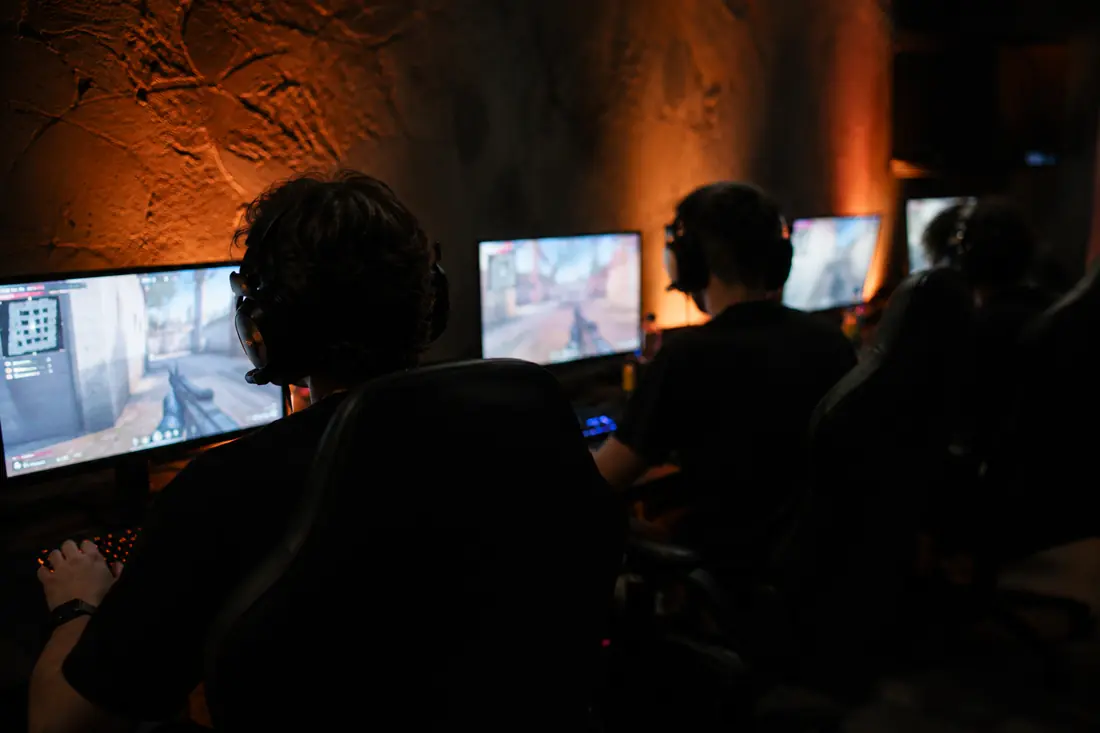 Grupo de jugadores concentrados frente a sus monitores durante una partida